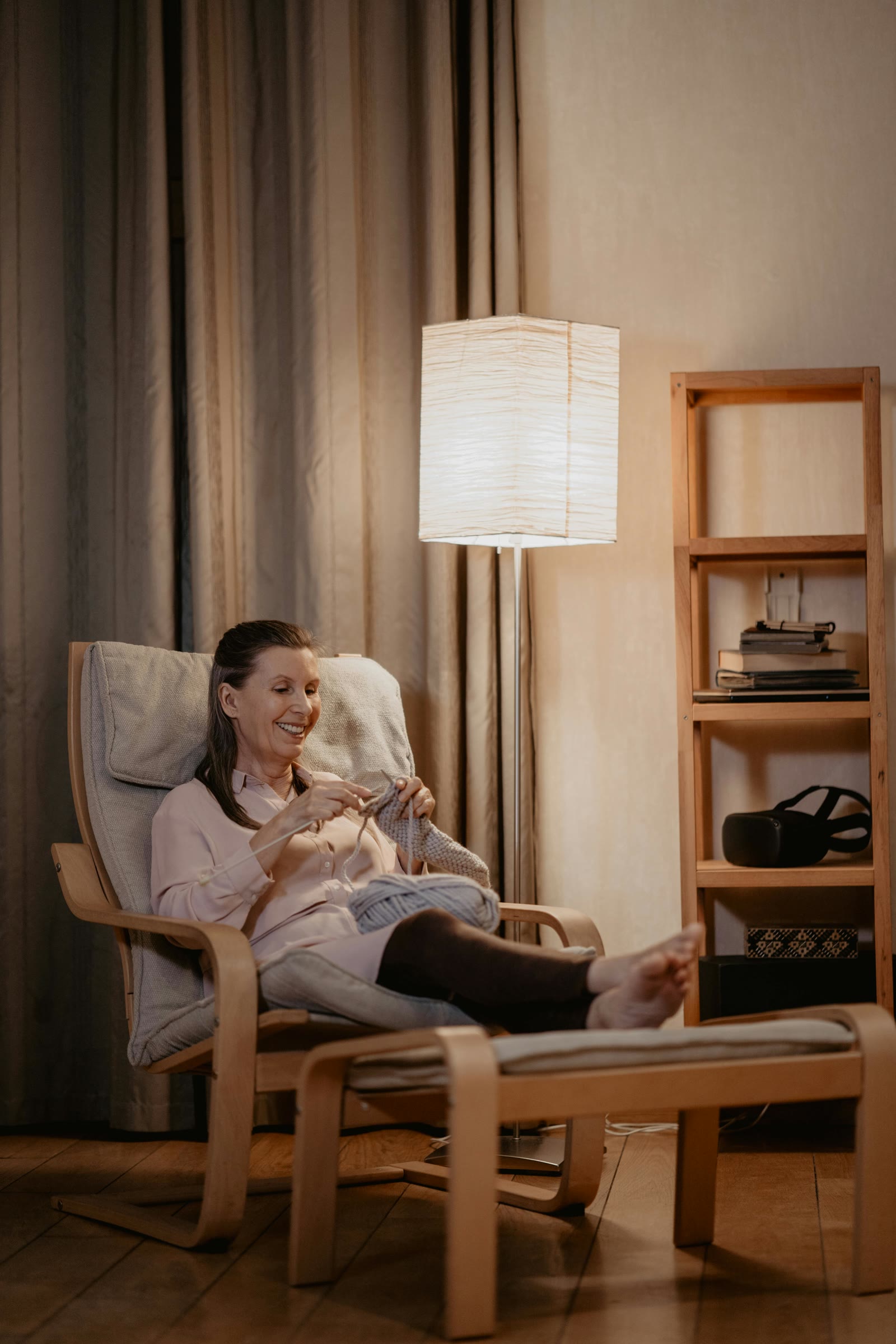 A woman reading in a chair by the bedroom window