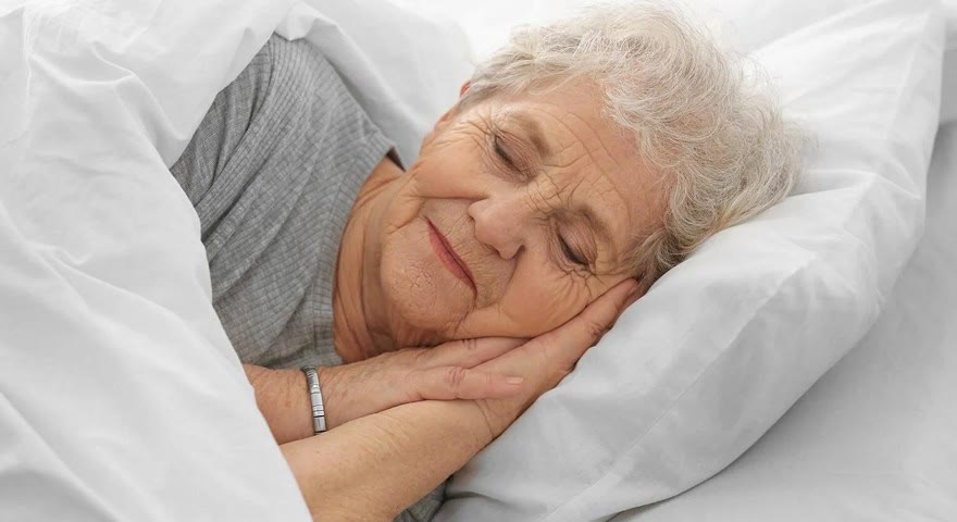An older woman asleep in her own bed